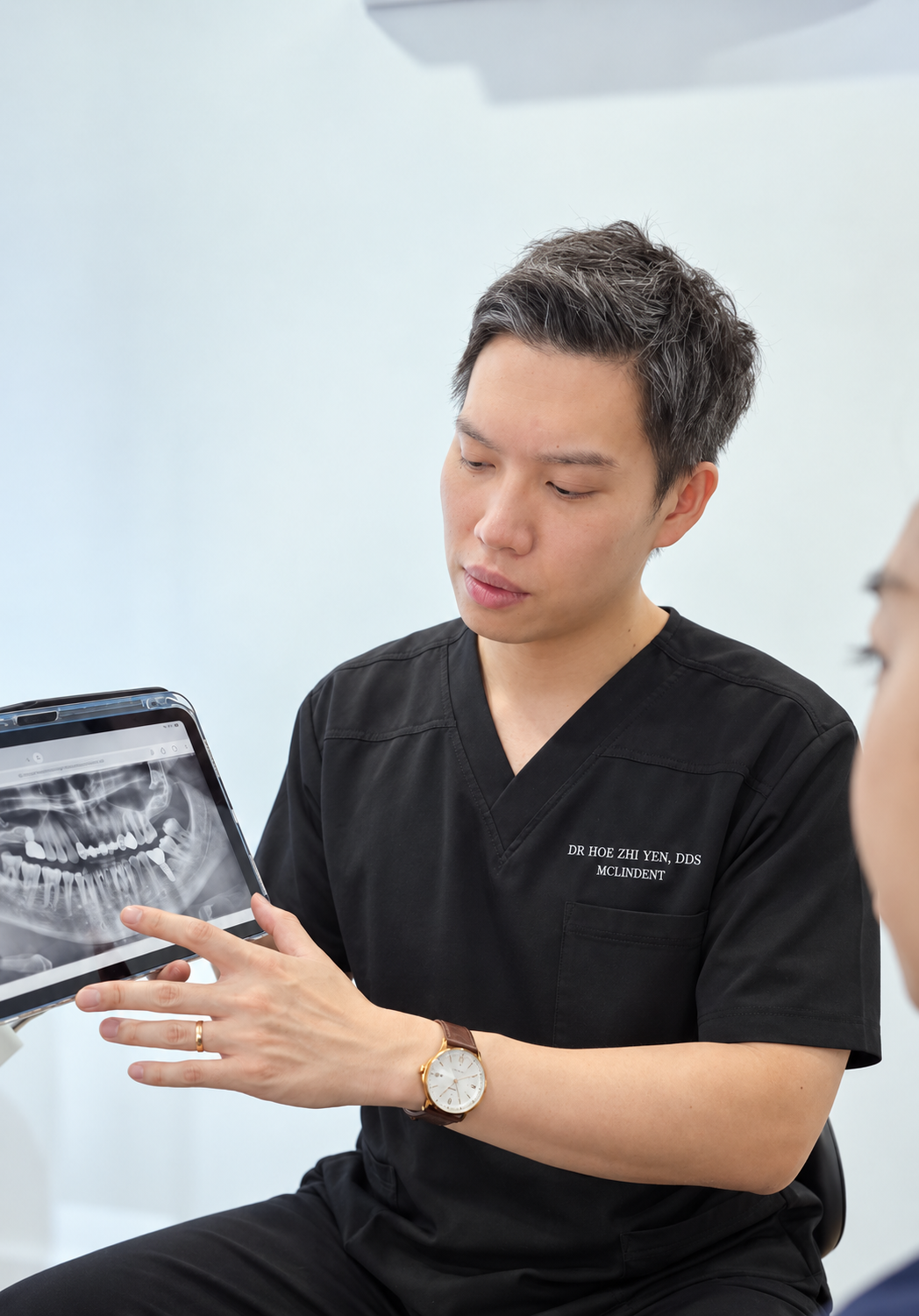 Dentist explaining a dental X-ray to a patient on a tablet